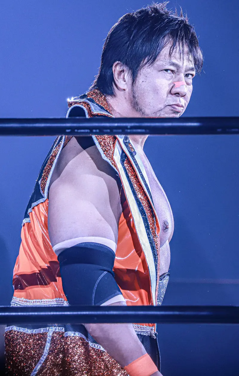Kojima in his orange robe, looking across the ring