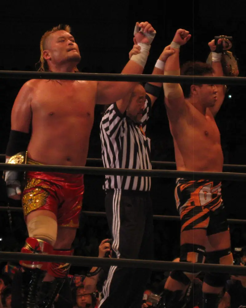 Tenzan and Kojima raise their fists next to the referee