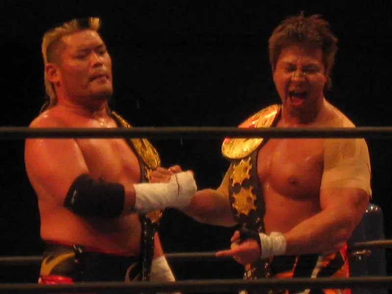Tenzan and Kojima shake hands, each with a tag title belt
